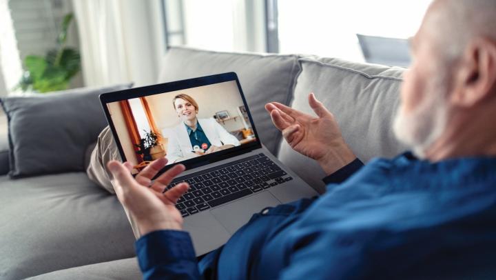 Person participates in a video call on a laptop while seated at home.