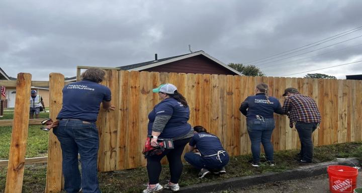Community volunteers build a fence at a transitional housing site to improve and support housing for veterans.
