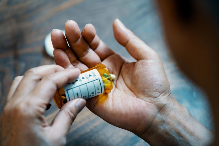 Close-up of a prescription medication container in a person's hand, representing pharmacy benefits.