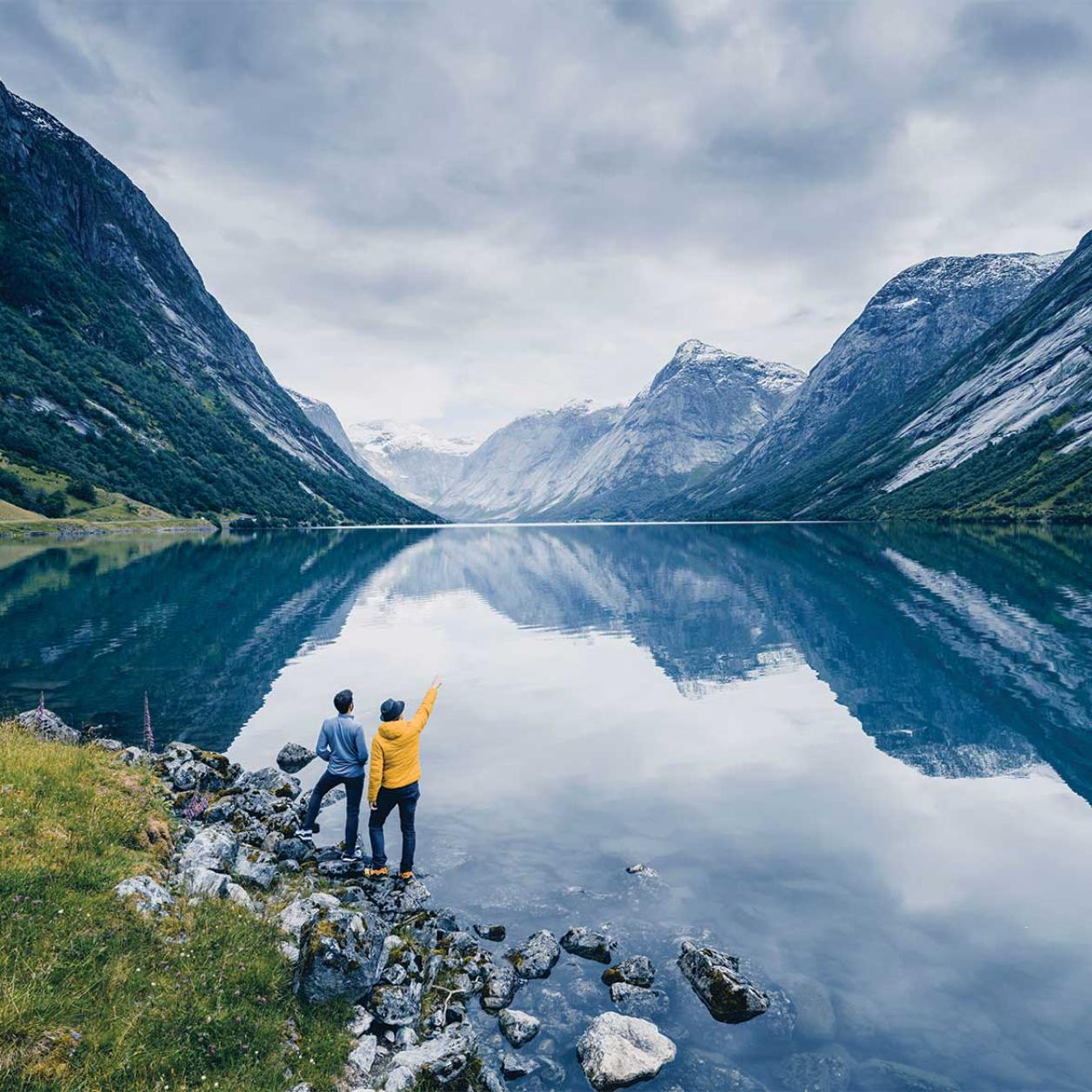 Two people beside a lake and mountains