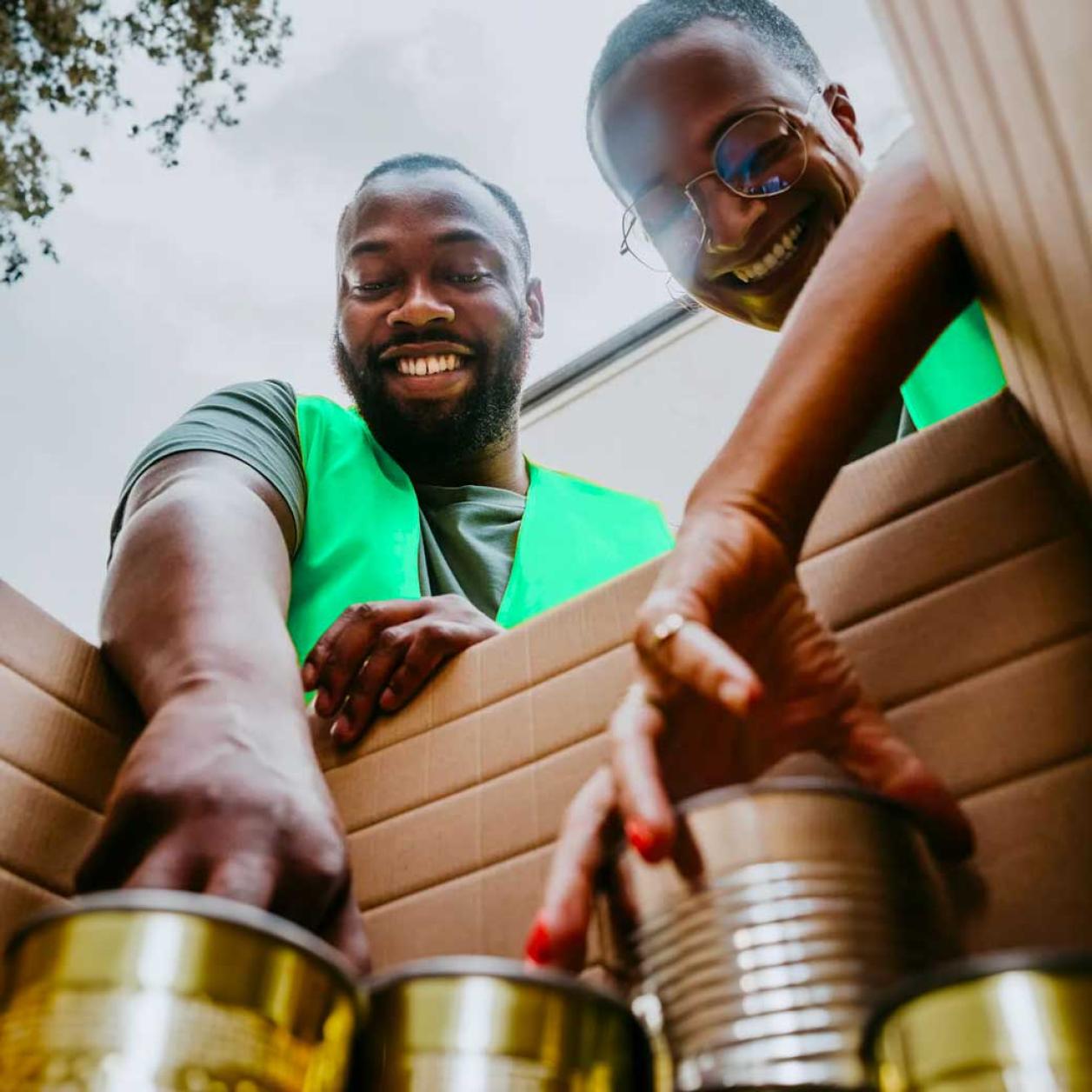 Two persons putting cans in a box